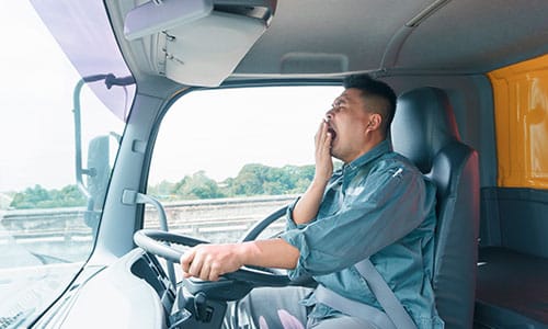 Truck driver yawning and looking sleepy behind the wheel